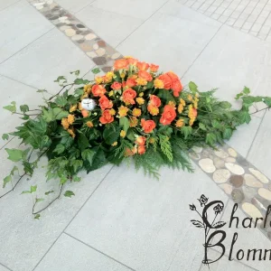 Sorgdekoration låg i orange toner med murgröna